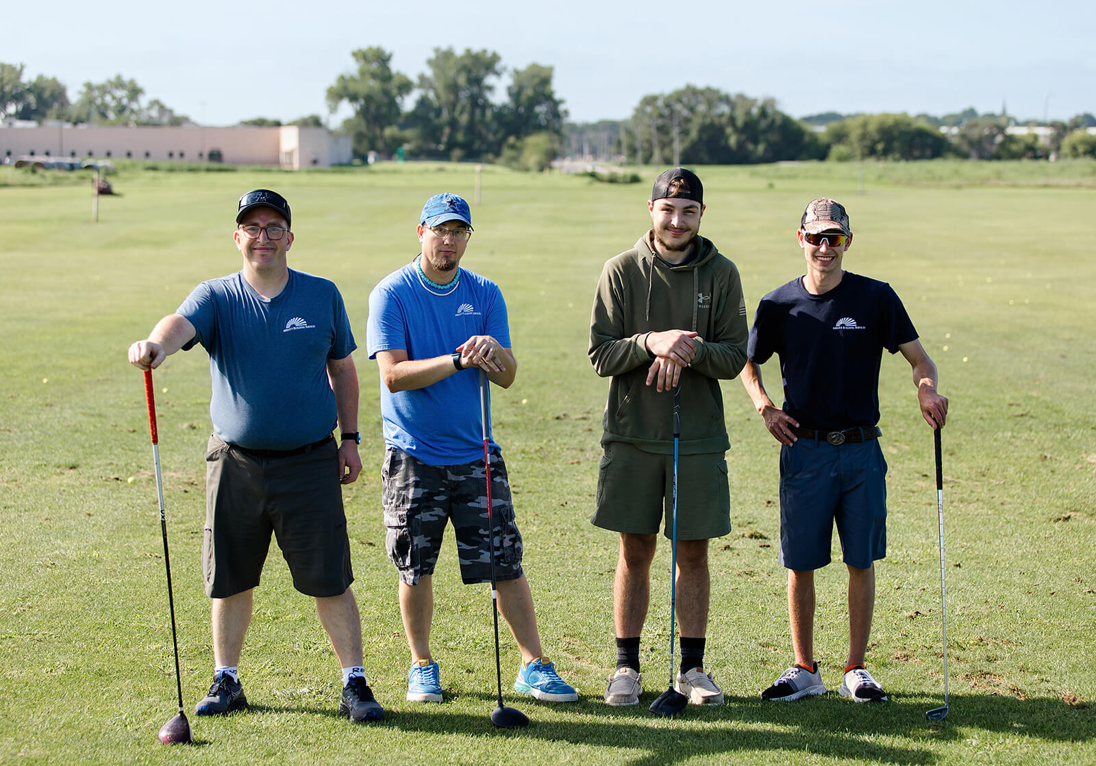 ABS79 Four men standing in a line holding golf clubs